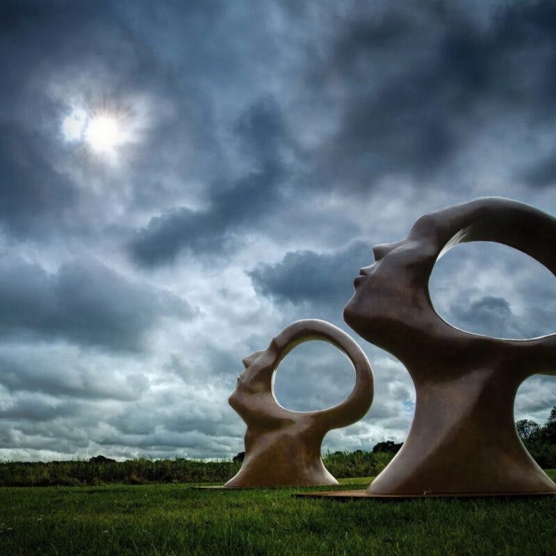 A sculpture named 'Search for Enlightenment' by Simon Gudgeon – 2 giant heads facing the sky